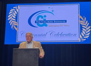 Ken Jones, former CI Board Chair, speaking at CI's 100th Anniversary Celebration in New Orleans, LA. Ken is speaking at a podium with a centennial background.