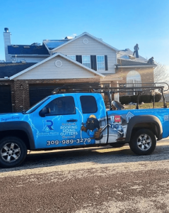Rainforcing Roofing service truck parked in front of a home with a roof replacement in progress.