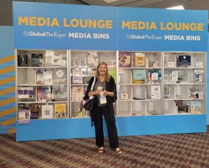 Cosmodoggyland team member posing in front of the Media Lounge at 2026 Global Pet Expo in Orlando, Florida