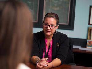 therapist, facing the camera, sitting across from a patient.