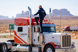 Founder of Aggregatemarkets.com stands on top of a branded semi-truck in a desert landscape.