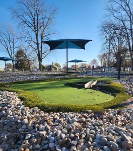 Mini Golf Course green at Cutler Park, Kokomo, IN, looks natural with sloping terrain and small wooden bridge amid rough turf