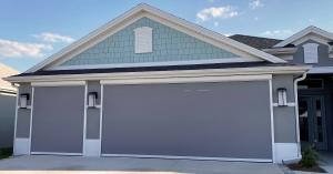 front view of a garage on a blue house with a warm grey Maestro Shield garage door screen closed