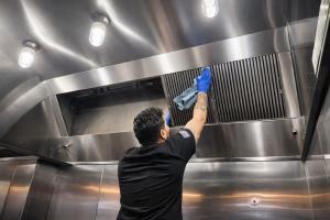 Technician performing deep cleaning of a commercial kitchen exhaust system to remove hidden grease and reduce fire risk