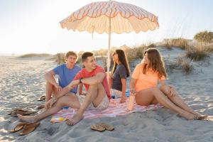 teens sitting under umbrella at the beach