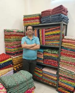 Dinesh Gupta, Founder of CTC Jaipur, at the company's Sanganer workshop surrounded by printed fabric inventory in block print, Bagru, screen print, and Bandhej across cotton and rayon bases.