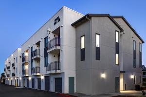 A photo of a new apartment style building with three stories, balconies, white and grey paint