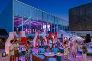 Guests socializing and dancing at an evening lifestyle event with colorful lighting at The Summer Social in Phuket.