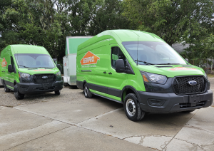 Two bright green SERVPRO branded Ford Transit vans with equipment trailers parked on job site in Tampa Florida ready for 24/7 biohazard cleanup and restoration response across Hillsborough County