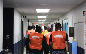 SERVPRO of Tampa East Central Temple Terrace cleanup crew in orange branded safety vests walking through commercial building hallway during active biohazard decontamination operation in Tampa Bay Florida