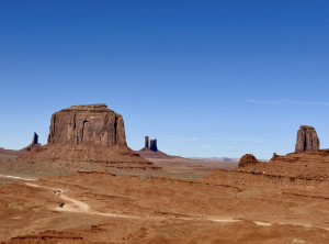 Wide view of West Mitten Butte rising from red desert landscape under a clear blue sky in Monument Valley.