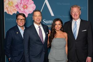 Four people—Jeff Arnold, Richard Lebowitz, Stephanie Malakie, and Hermann Elger—stand together at the Forbes Travel Guide Summit in Monaco, celebrating Malakie’s award.
