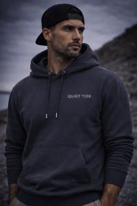 Quiet Tide minimalist hoodie in dark neutral tone featuring subtle logo, designed for calm, confident streetwear style