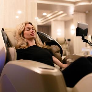 Woman relaxing in a zero-gravity massage chair at Unwind Massage Lounge in Dallas, a touchless walk-in massage experience near SMU