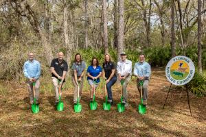 Conservation leaders and and an elected offical hold green shovels for the groundbreaking of a new trail