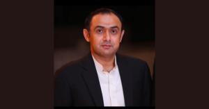 Oxi Fresh Carpet Cleaning franchisee Malik Khar poses for a portrait in a black suit with a white shirt.