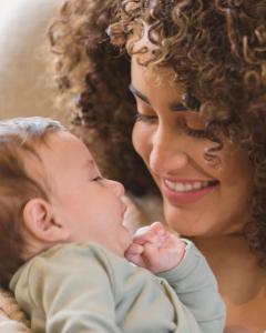 Mother smiling at her baby in a soft nursery setting, representing comfort, dryness, and care for sensitive skin.