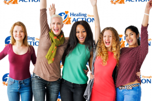 Women at the Healing Through Action Conference in front of the banner