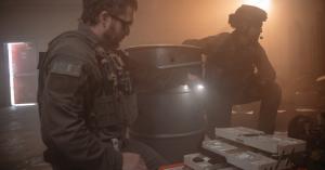 Two police tactical officers in protective gear prepare medical supplies from an organised case inside a smoke-filled indoor environment, illuminated by warm backlighting, highlighting readiness and emergency response conditions.