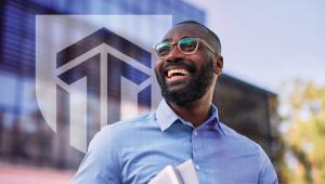 A student smiles in front of the Excelsior University logo