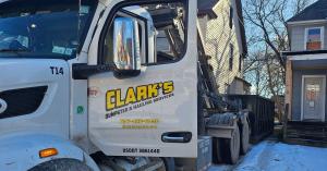Clarks Dumpster and Hauling Services branded delivery truck at residential dumpster drop off in Elmira NY