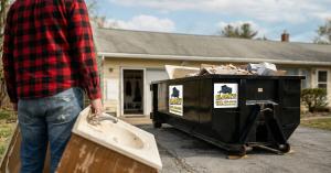 Homeowner loading debris into Clarks Dumpster roll off container during residential garage cleanout