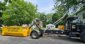 Clarks Dumpster hook lift truck delivering yellow roll off dumpster to residential neighborhood in Elmira