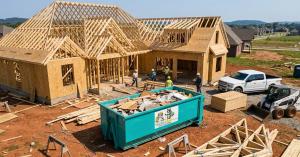 Trash Pandy teal 20 yard dumpster at new home construction site with crew and framing in Middle Tennessee