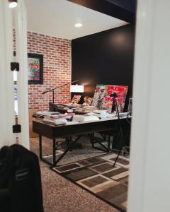 A focused view of a professional desk in a modern office, featuring a brick accent wall, creative "Dream Big" artwork, and project documents under warm lighting.