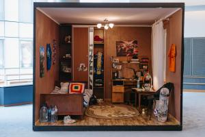 A life-size replica of a Ukrainian teenager's bedroom, displayed inside the European Parliament building in Brussels. The room contains a bed, desk, wardrobe, skateboard, and personal belongings, frozen in time