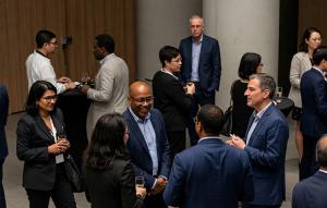 Business professionals networking and conversing at a corporate event with drinks in hand.