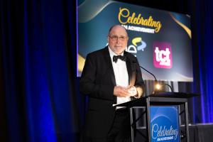 An older white man with glasses, Joe Allison, accepts his award.