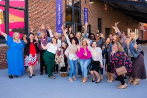Group of women business owners cheering outside Elevator Co-Warehousing's workspace during a networking event.