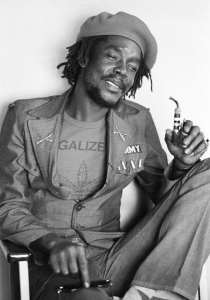 Image of Peter Tosh sitting against a wall: The messages from Peter Tosh continue to resonate as a lasting symbol of resistance, identity, and cultural change. ©️2026 Kim Goittlieb / Under license by Tosh Holdings LLC