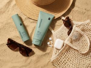 hypothesis™ eczema therapy cream and healing spray displayed on sand with sunglasses, straw hat, mesh tote bag, and wireless earbuds