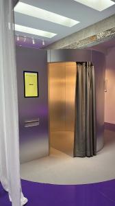 Picture of futuristic photo booth, silver with a grey curtain and purple floor