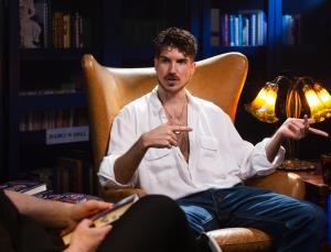 Joey Graceffa sits in a leather library chair, opposite Chris Collins, the interviewer. 