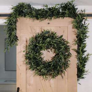 9-foot faux olive garland and 30-inch olive wreath styled on a wooden door, featuring realistic greenery for seasonal home decor.
