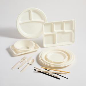 An assortment of cream‑colored Wave Ware compostable tableware—including plates, trays, bowls, utensils, and chopsticks—arranged neatly on a light background, showcasing NantBioRenewables’ sustainable products made from Ocean Calcium Sand.
