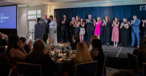 IHG representative Kevin Shockling handing a trophy to members of the Daly Seven leadership team on a stage at an awards gala.
