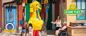 Big Bird character greets children and adults at Sesame Place Philadelphia, with a Certified Autism Center seal visible.