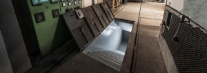 Open blast shelter hatch with steel-reinforced doors and descending stairs inside a hardened military bunker — the type of critical infrastructure ArmorThane polyurea blast mitigation systems are designed to protect