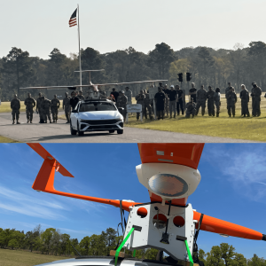 A drone attached to the top of car ready for takeoff in front of a group of U.S. military personnel, and closeup of receiver attached to underside of UAS wing