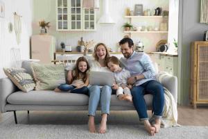 Family of four sitting on a sofa and viewing a lap-top within the home