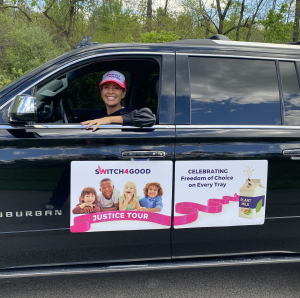 Vegan Olympic Medalist Dotsie Bausch waves while seated in a black vehicle on The Justice Tour.