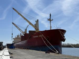 Cargo ship docked at the Illinois International Port District at the Lake Calumet Terminal Facility, marking the first international vessel of the 2026 shipping season, with cranes, dock infrastructure, and water visible in the background.