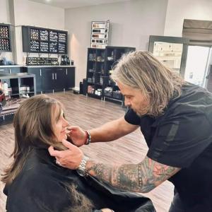 Just Jeff adjusting a client’s hair during a styling consultation inside a modern professional salon.