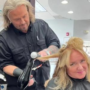 Hairstylist Just Jeff blow-drying and round-brushing a client’s blonde hair during a salon styling session.