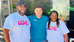 Love Mobile® co-founders Wade Dunn Jr. and Koddi Dunn standing with a nonprofit community partner in Love Mobile branded shirts, representing the company's Nonprofit Partners program.