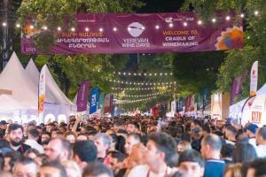 Aerial view of thousands of people celebrating at the Yerevan Wine Days festival on Saryan Street, Armenia, featuring wine tasting booths, festive lights, and a cosmopolitan urban atmosphere.